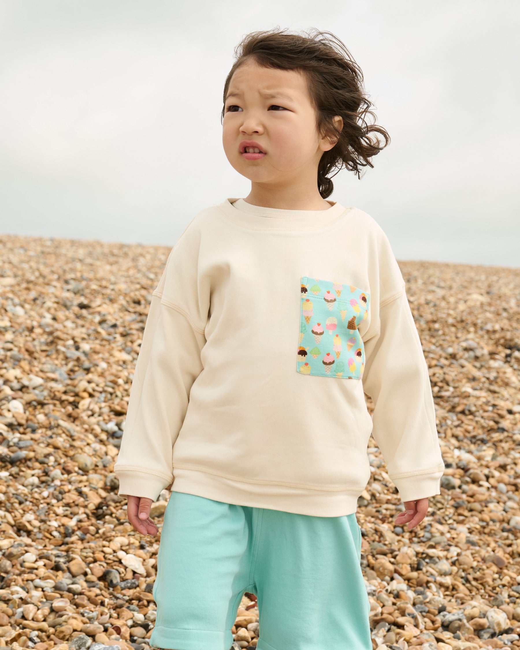 Ecru sweatshirt with oversized turquoise ice cream print chest pocket.