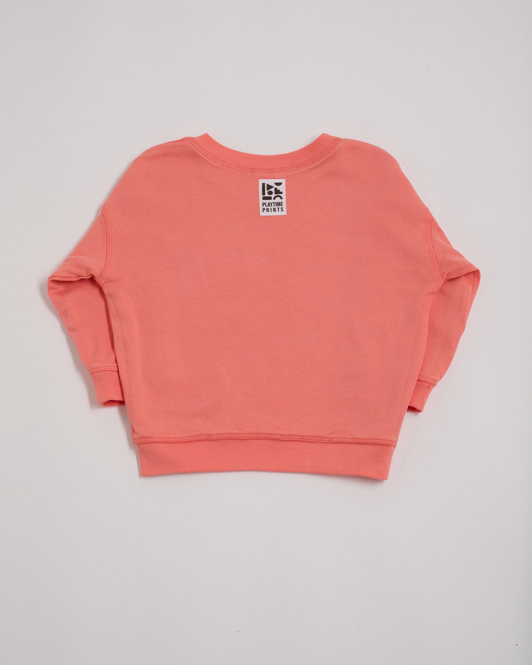 Back of coral sweatshirt showing Playtime Prints brand label.