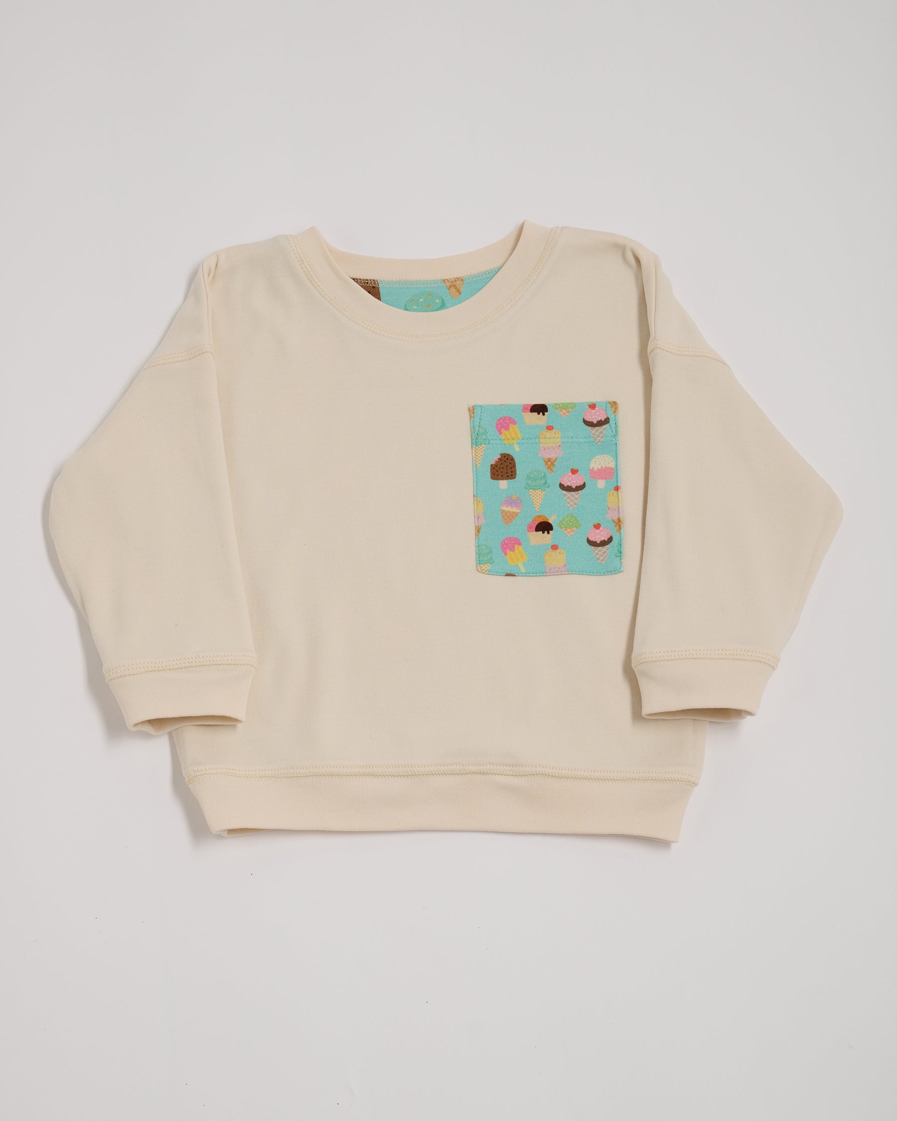 Front of ecru sweatshirt with oversized turquoise ice cream print chest pocket.