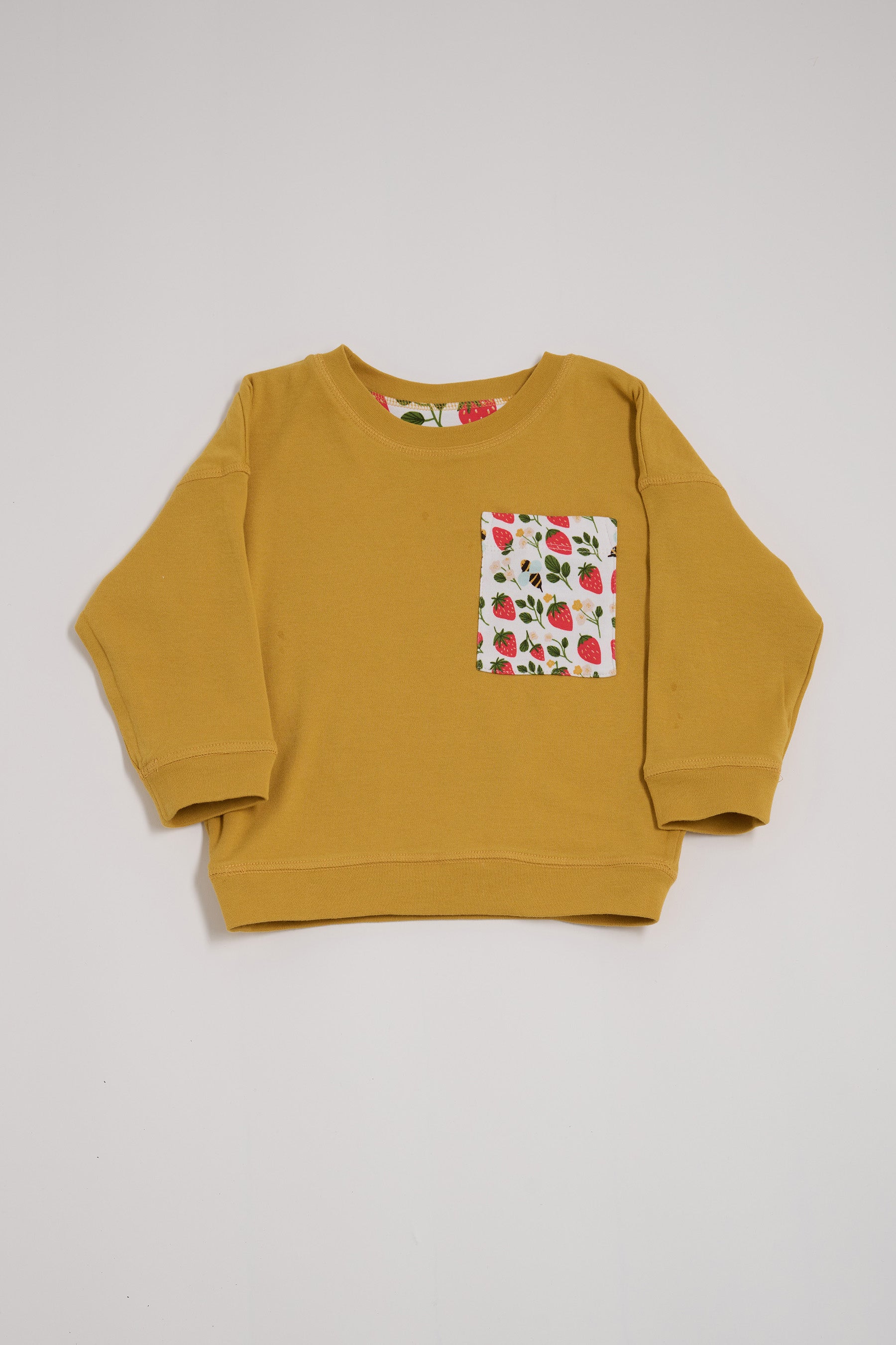 Front of honey coloured sweatshirt featuring oversized strawberry and bees chest pocket.