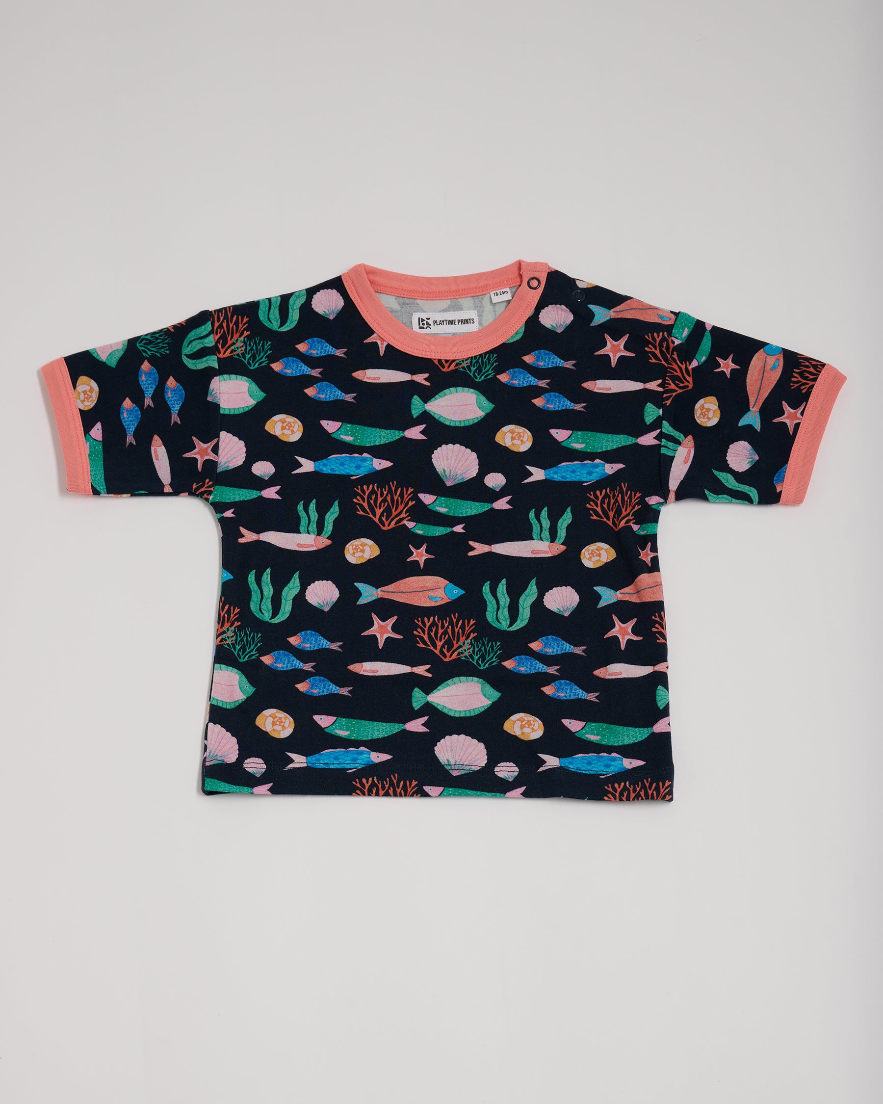 Front of short sleeved t-shirt featuring an all over vibrant navy fish print, with contrast coral neck and sleeve trim and neck poppers.