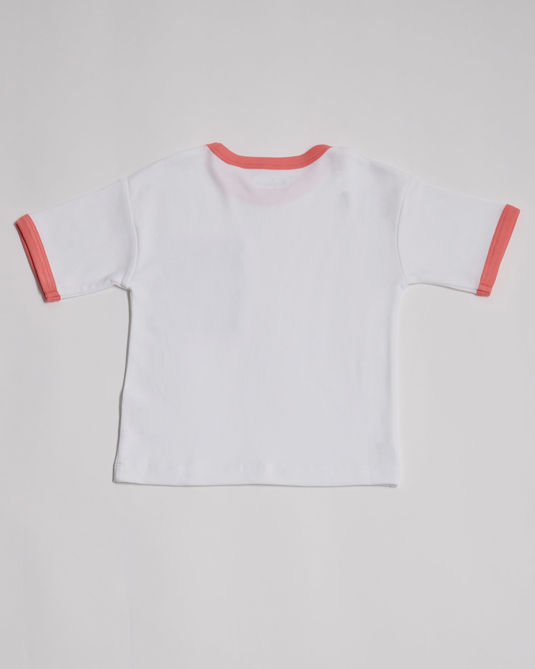 Back of white short sleeved t-shirt with coral neck and sleeve trim.