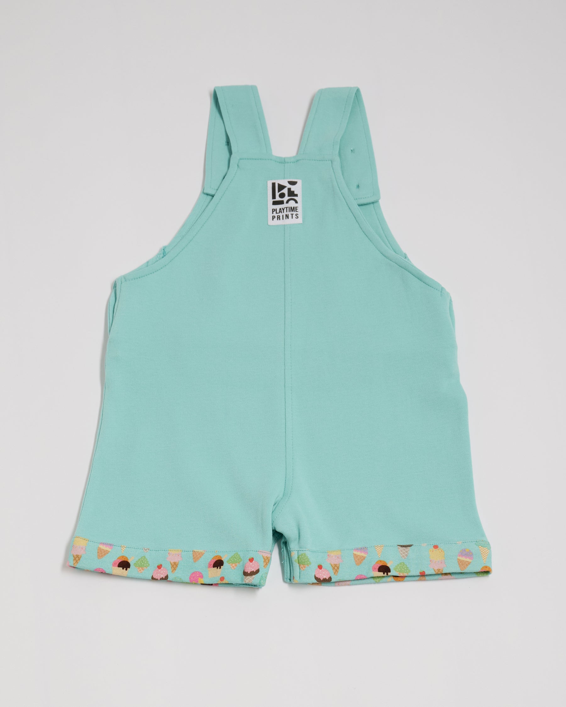 Back of turquoise short dungarees with bright ice-cream print turn-ups and Playtime Prints brand label.