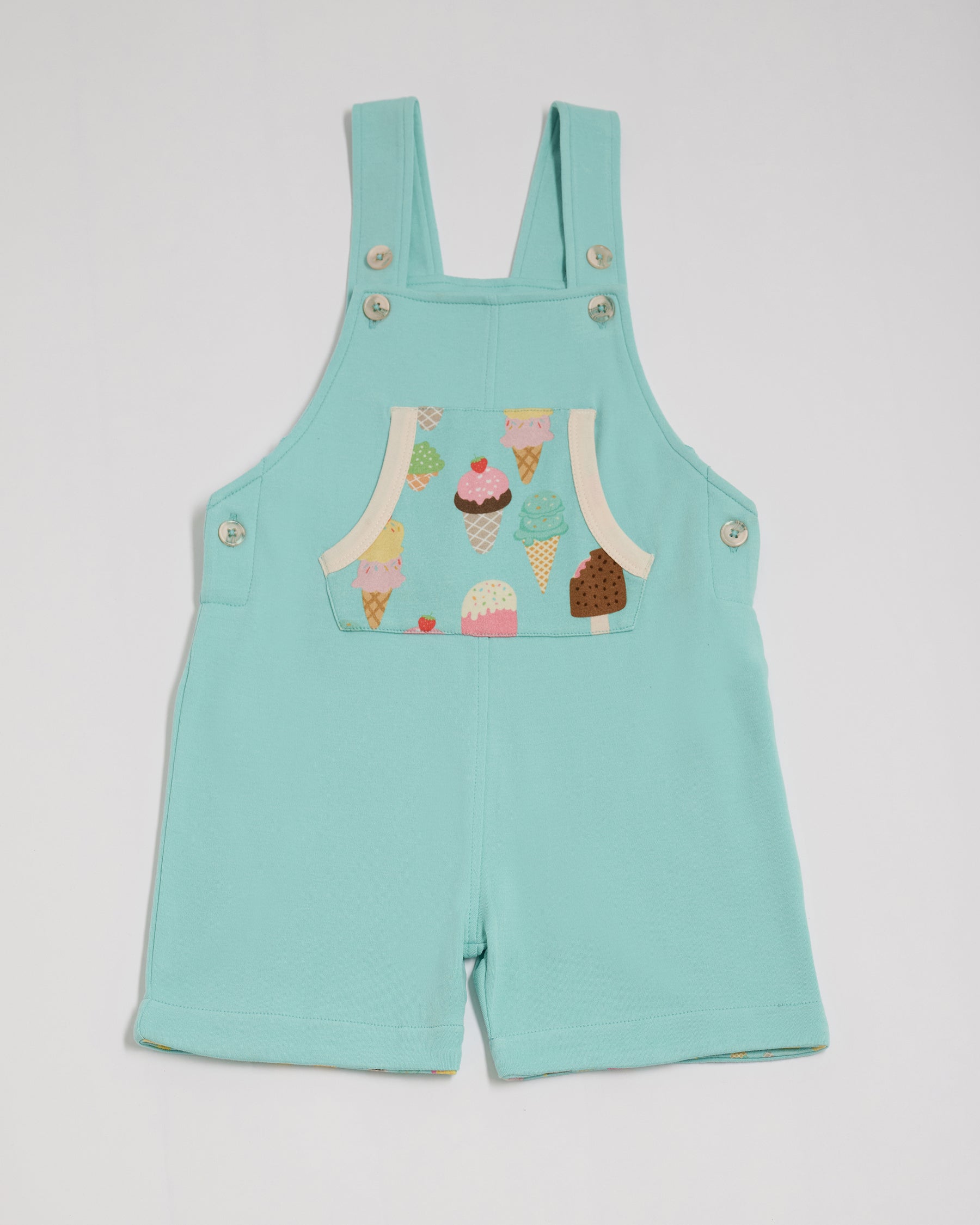 Front of turquoise short dungarees with bright ice cream print pocket, vanilla buttons and vanilla trim.